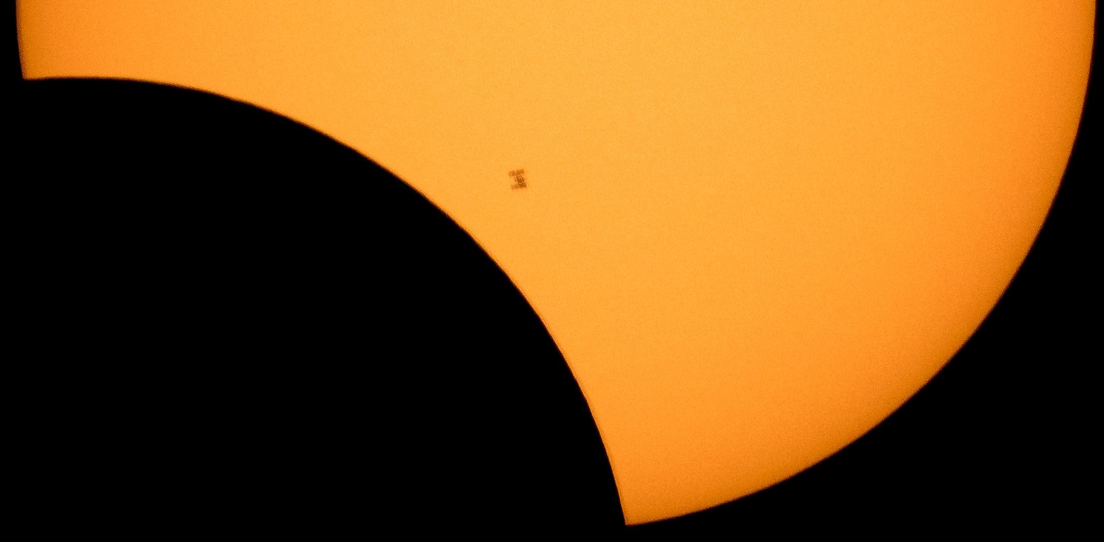 The International Space Station, with a crew of six onboard, is seen in silhouette as it transits the Sun at roughly five miles per second during a partial solar eclipse, Monday, Aug. 21, 2017.<br />Credits: NASA/Bill Ingalls